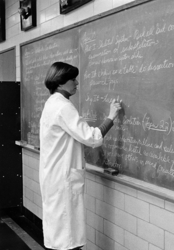 Carol Crafts standing in a classroom writing on a chalkboard.
