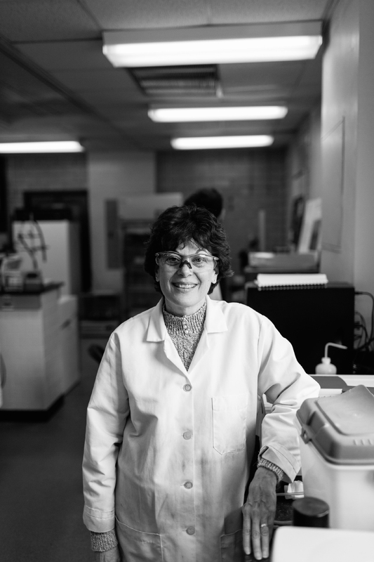 Kathleen Cornely poses for a photograph in a laboratory wearing a lab coat and safety glasses.