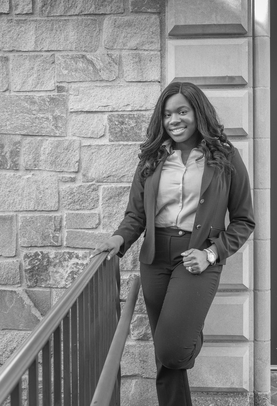 Taiwo Adefiyiju-Monwuba poses at the top of a set of stairs in front of a stone building.