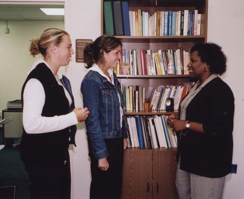 Wanda Ingram stands in an office talking to two students.