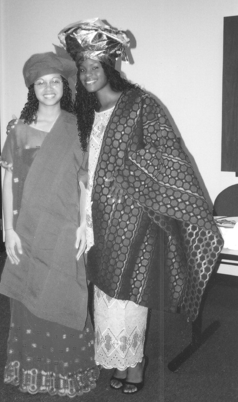 Two students posing for a photograph in a classroom wearing traditional clothing.