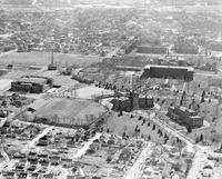 Aerial view of Providence College with multiple buildings, open fields, tree-lined paths, and a surrounding residential neighborhood.