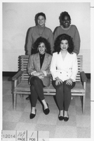 Four students who are part of Students Organized Against Racism pose for a photograph. Two are sitting on a bench and the other two are standing behind them.