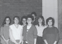 Several students pose for a photograph in brick walled room.