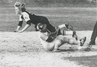 Softball game showing a player from Providence College sliding into a base while another player from the University of Rhode Island attempts to tag them out.