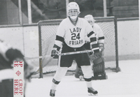 Two hockey players in Lady Friars uniforms. One is in the goal and the other skates on the ice with a hockey stick in hand.