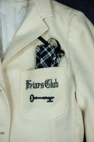 Close up of the Friars Club embroidered logo on a white blazer. The logo is of a key.