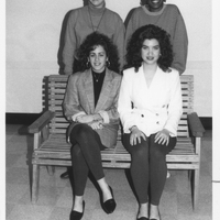 Four students who are part of Students Organized Against Racism pose for a photograph. Two are sitting on a bench and the other two are standing behind them.