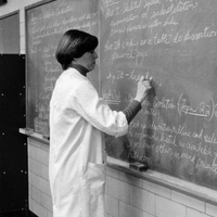 Carol Crafts standing in a classroom writing on a chalkboard.