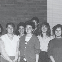 Several students pose for a photograph in brick walled room.