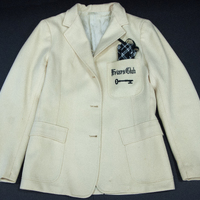 A Friars Club white jacket with a black and white checkered pocket square. The words 'Friars Club' and a key are embroidered on the front pocket.