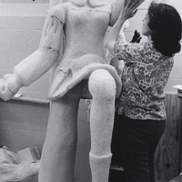 Sister Bernadine M. Egleston working on a large sculpture of a woman.
