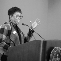 Jackie Peterson standing at a podium giving a speech.