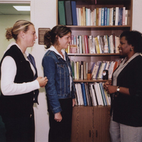 Wanda Ingram stands in an office talking to two students.