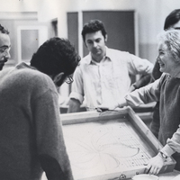 Suzanne D'Avanzo standing with students in a classroom holding a canvas.