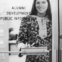 Karen Roy standing in front of a glass door that reads 'Alumni Development Public Information.'